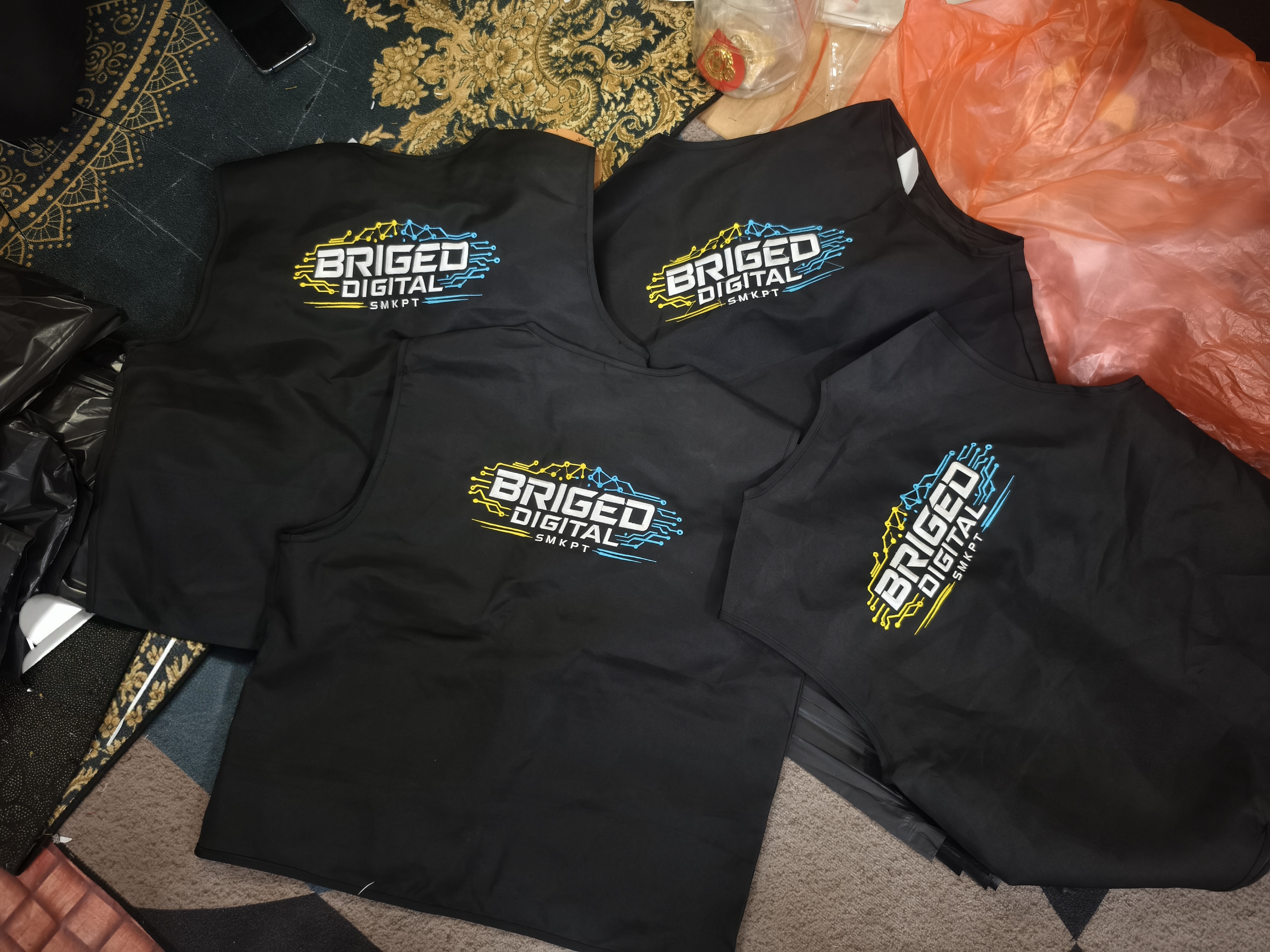 Vest hitam dengan logo Briged Digital SMKPT berwarna biru, kuning dan putih