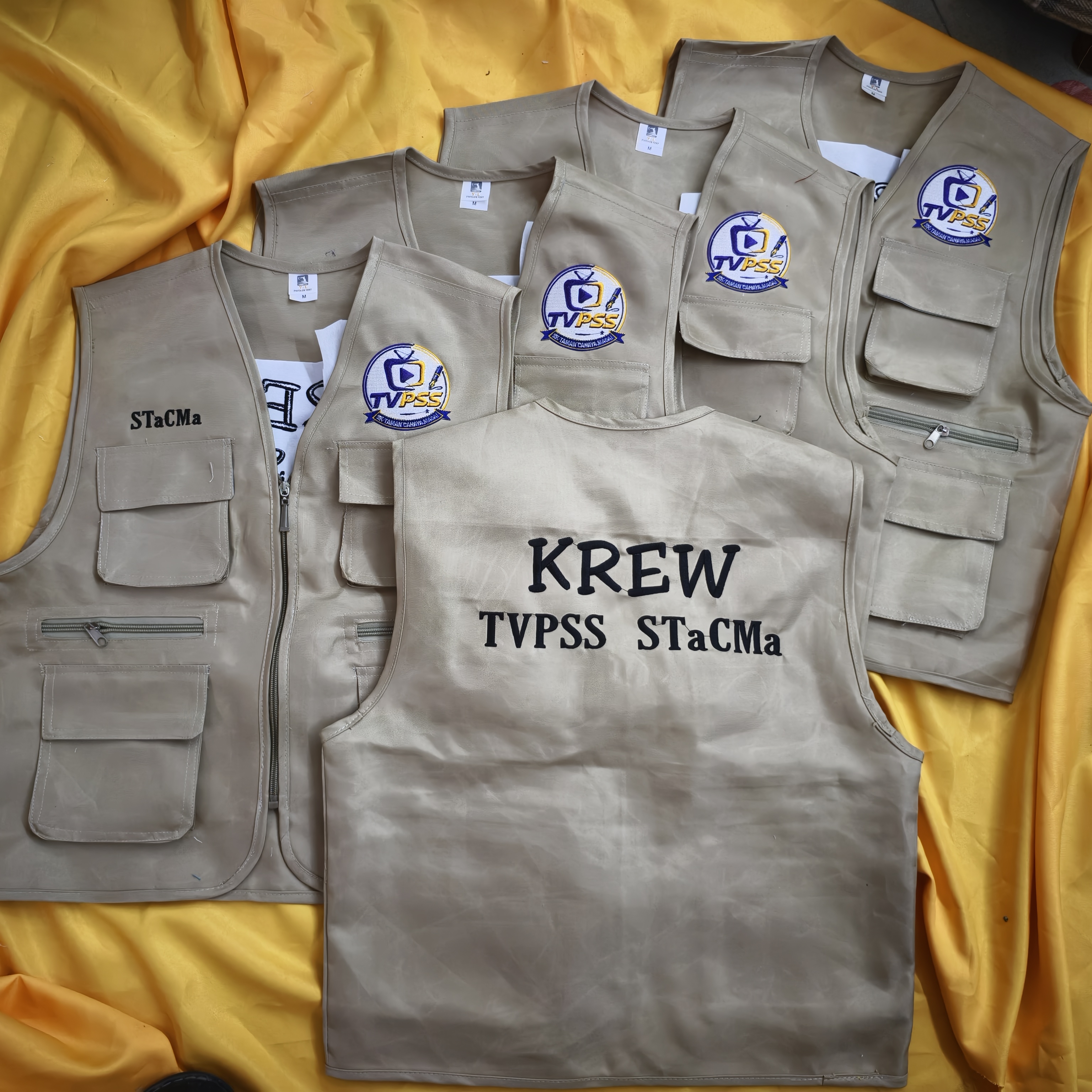 Vest krim berlambang TVPSS dengan tulisan Krew TVPSS STaCMa di atas kain kuning