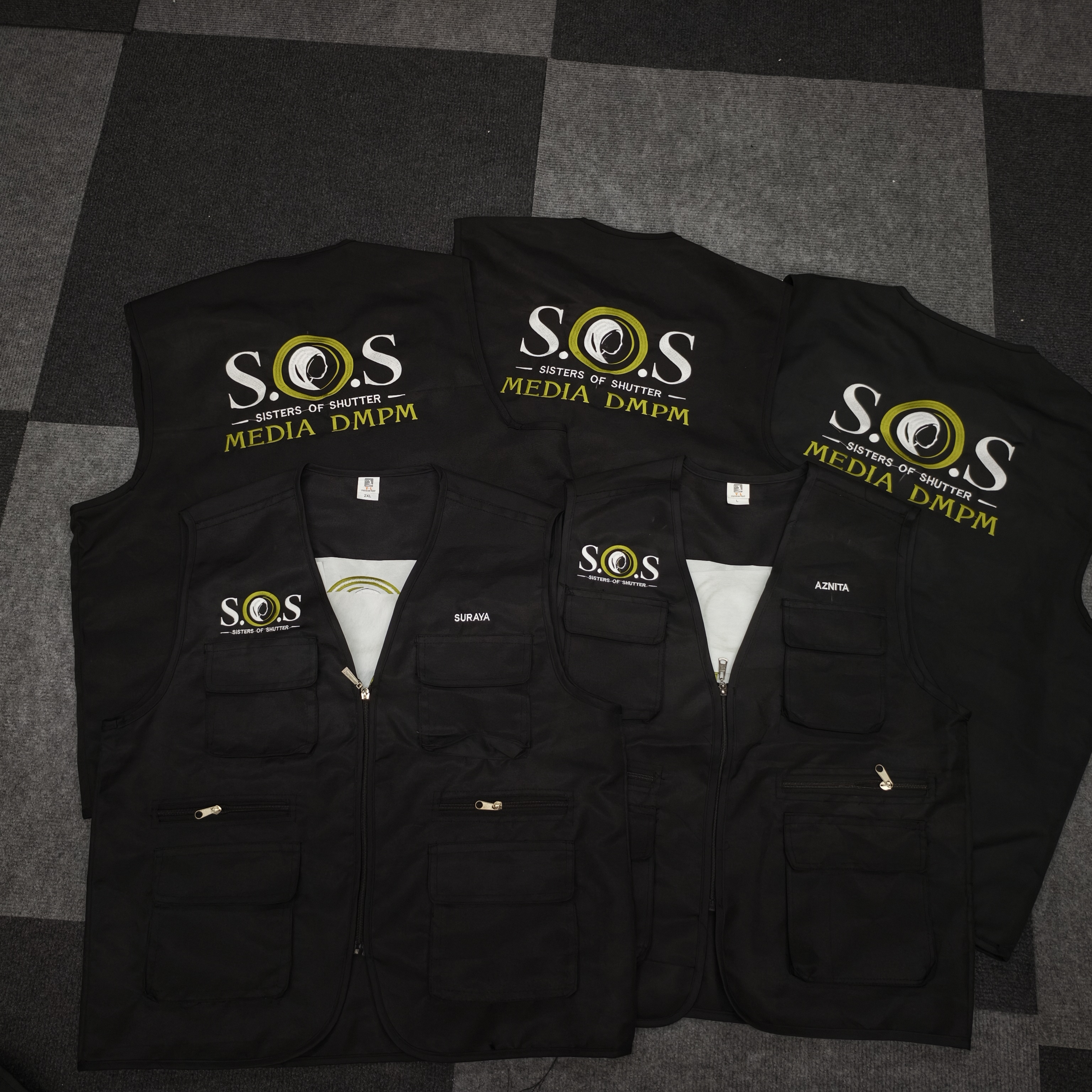 Vest hitam dengan logo S.O.S Sisters of Shutter Media DMPM dan sulaman nama