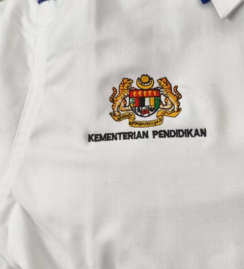 Sulaman Jata Negara dan tulisan Kementerian Pendidikan pada baju putih